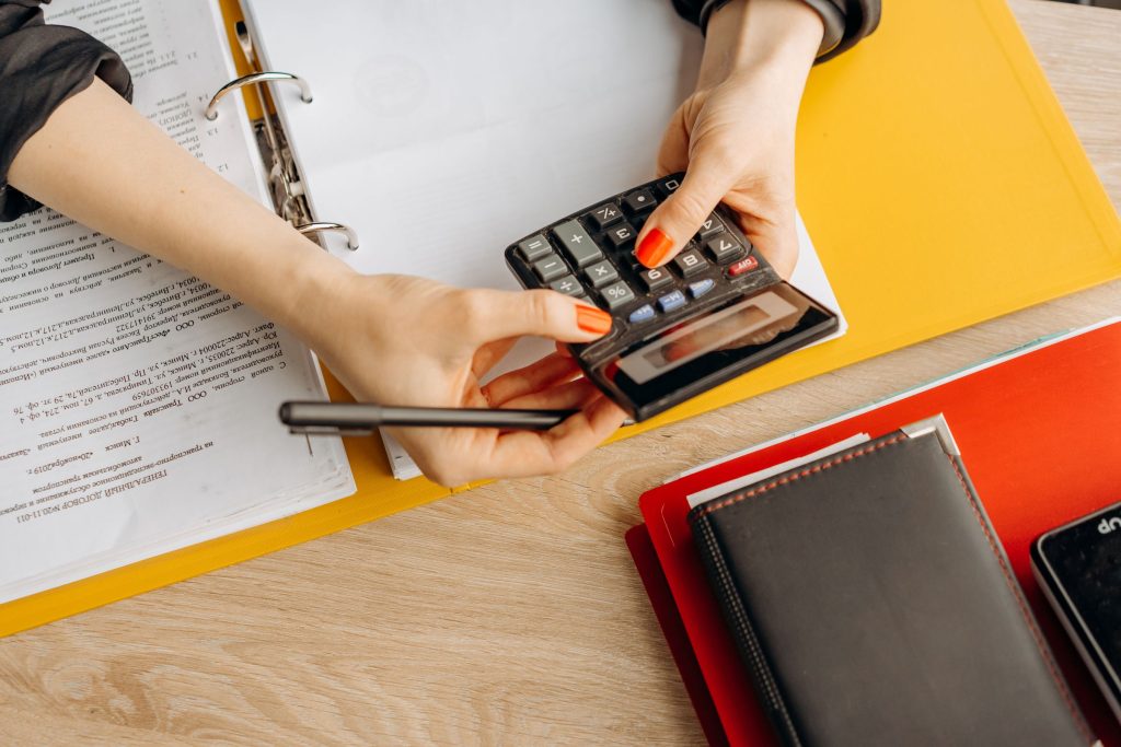 Comptable utilisant une calculatrice avec des dossiers et pièces comptables